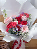 Bouquet of red and pink roses with white flowers wrapped in white paper, branded '5 Stones Florist'.