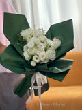 Bouquet of white flowers wrapped in green paper 
