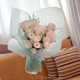 Bouquet of pink and white flowers wrapped in light blue paper 